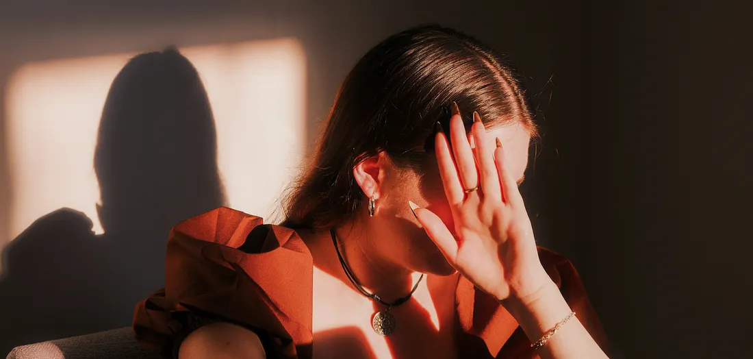 Trauma Flashbacks and PTSD Are Not Weaknesses. Image of woman covering her face with her hand.